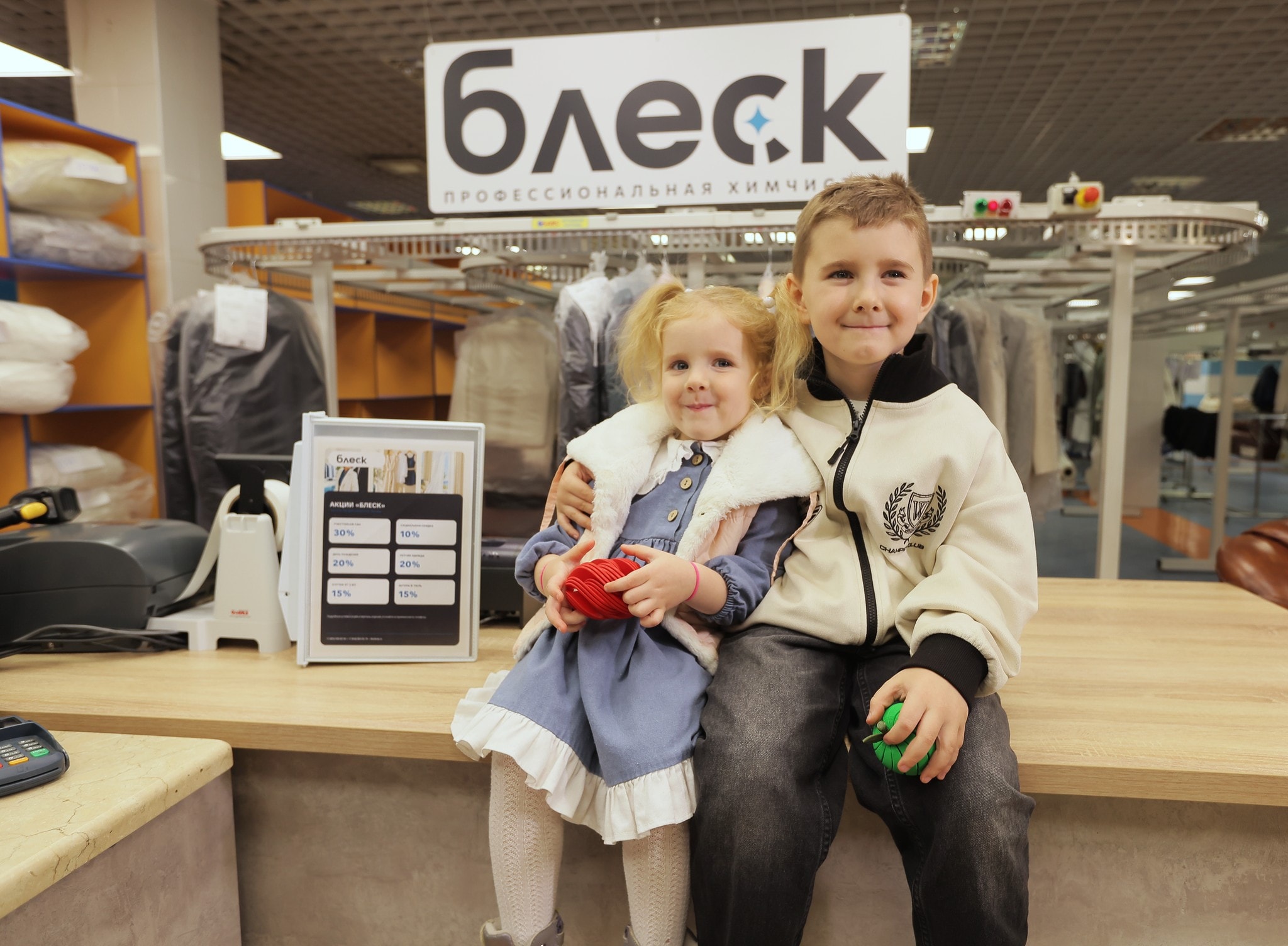Двое детей сидят на стойке приёма «Блеска»